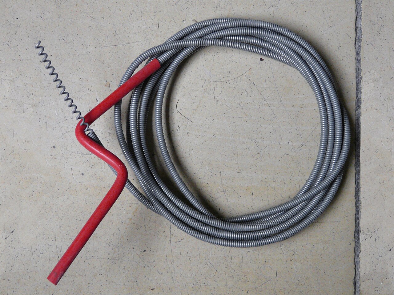 Powered drain-cleaning auger with coiled cable on a workshop floor